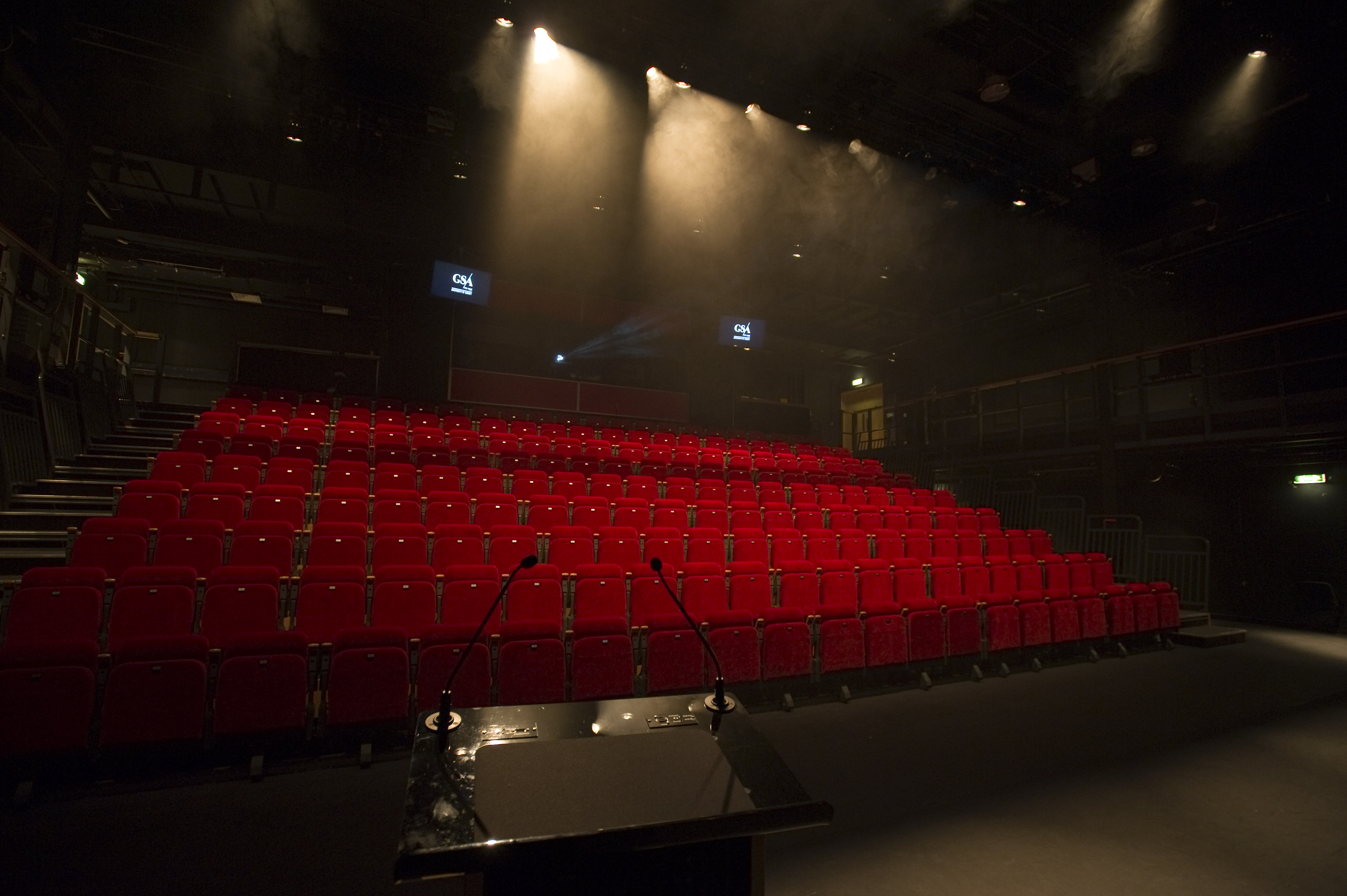 Theatre hall with red velvet seats and staging lights.